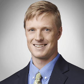 A person wearing a suit and tie smiling at the camera
Description automatically generated