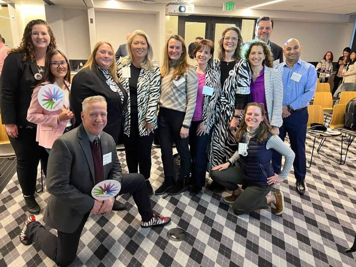 Twelve employees from Ultragenyx pose for a photo with many of them wearing black and white zebra patterned clothing to indicate their support for rare disease patients.